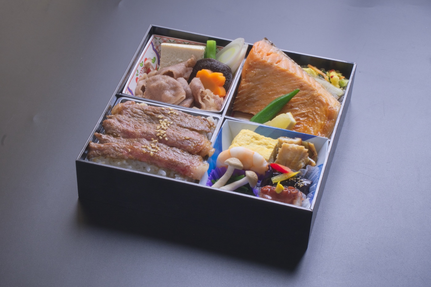 （小手指しみずの）牛すき焼き、鮭腹身焼き、ステーキ松花堂仕出し弁当の写真